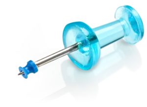 Photo of micro ear drain tube for ENT medical devices, with thin wall molding, shown on the tip of a thumbtack, by Isometric Micro Molding