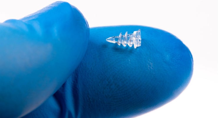 Picture of a bioresorbable tissue repair medical device for orthopedics, shown on a gloved finger, by Isometric Micro Molding