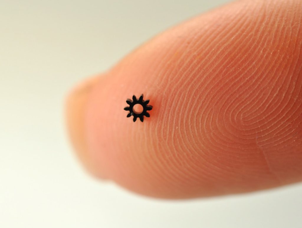 Picture of PEEK Micro Gears on a finger tip, used in pharmaceutical drug delivery devices, by Isometric Micro Molding