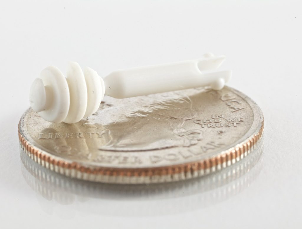 Photo of a micro component for ENT medical devices, with two shot molding, shown on a US quarter, by Isometric Micro Molding