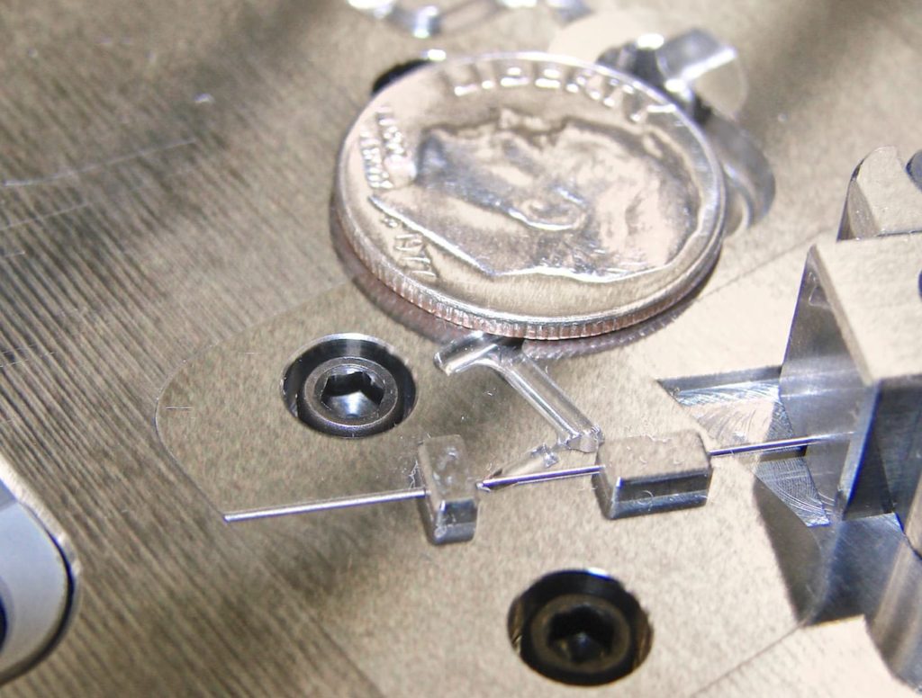 Picture of polycarbonate micro fluidics cannula sleeve for diabetic medical devices, shown next to a dime, by Isometric Micro Molding