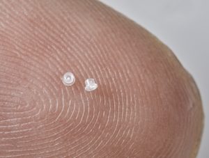 Picture of long term implantable micro drug delivery devices for cancer treatment, on a fingertip, by Isometric Micro Molding