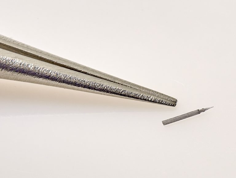 Photo of micro component for medical devices next to the tip of a surgical tool, by Isometric Micro Molding