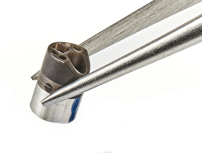 Picture of stainless steel catheter tip with micro features held by tweezers and used for surgical navigation medical devices, created by Isometric Micro Molding