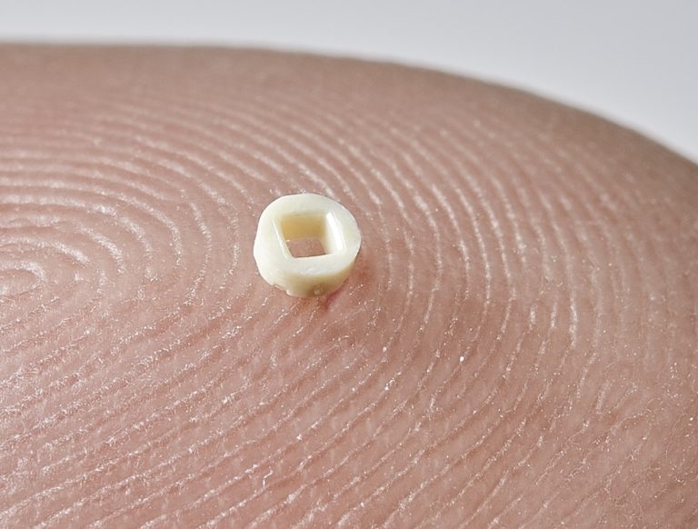 Photo of in vitro device micro component, for reproductive support medical devices, shown on a finger tip, by Isometric Micro Molding