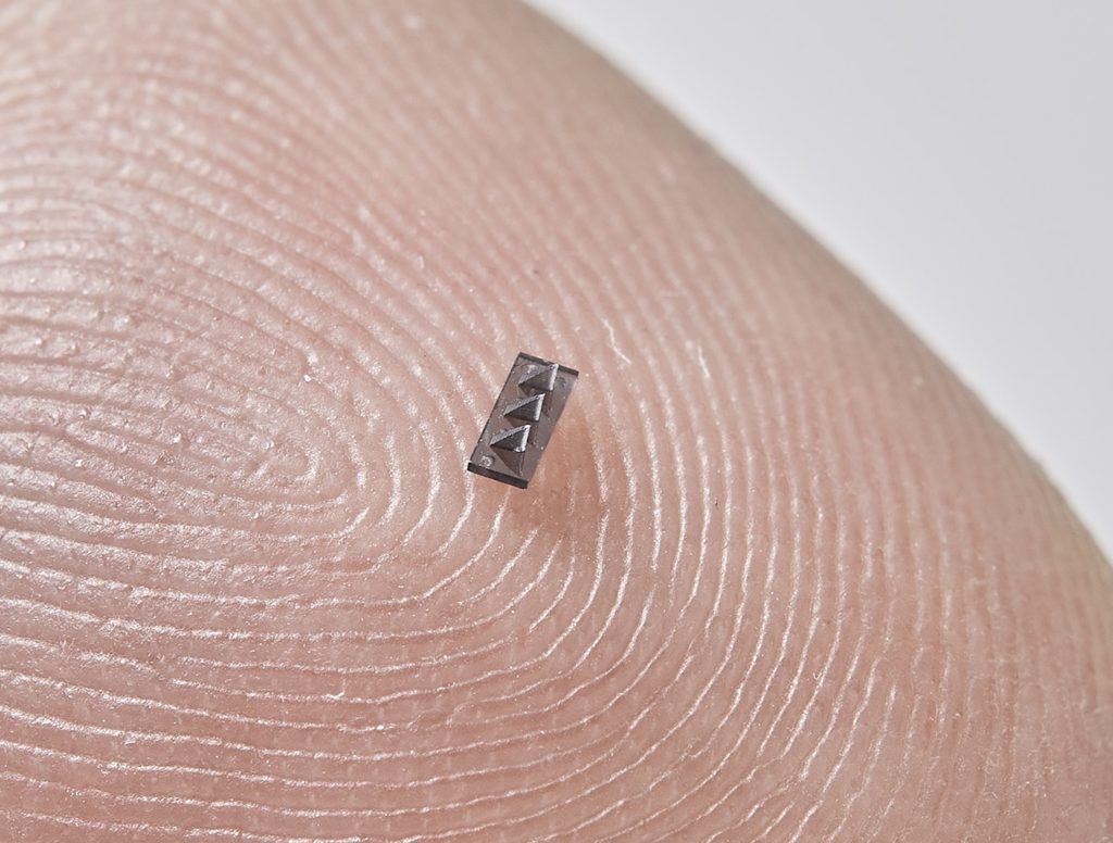 Pharmaceutical photopolymer, micro barb needle produced via M3D printing shown on fingertip by Isometric Micro Molding